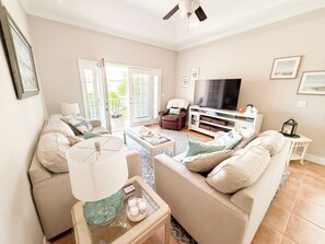 A living room with a sofa, armchair, coffee table, TV, and a ceiling fan. - Walk to the beach. Two pools, hot tub, tennis. (St. Augustine)