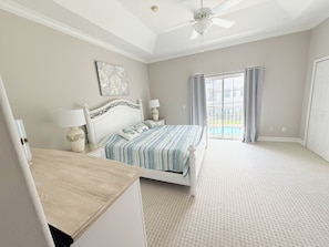 A bedroom with a bed, a ceiling fan, a window with curtains, and a view of a swimming pool. - Walk to the beach. Two pools, hot tub, tennis. (St. Augustine)