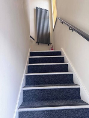 A staircase with a handrail and a fire extinguisher at the bottom. - Studio Sleeps 2 with Parking (Belfast)