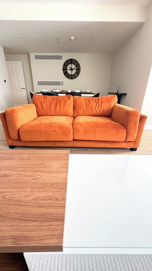 A modern living room with a sofa, a dining table, and a wall clock. - Private Elevator Marylebone Apartment Central Lond (London)