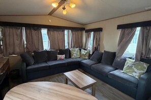 A living room with a sectional sofa, a wooden coffee table, and a ceiling fan. - Serene Lodge Retreat in Clacton (Clacton-on-Sea)