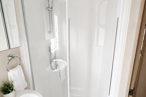 A bathroom with a glass shower enclosure, a white sink, and a towel rack. - Serene Lodge Retreat in Clacton (Clacton-on-Sea)