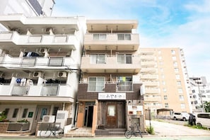 A multi-story residential building with balconies, a bicycle parked outside, and a sign indicating a business establishment. - Haimu Ekiminami 2 (Fukuoka)