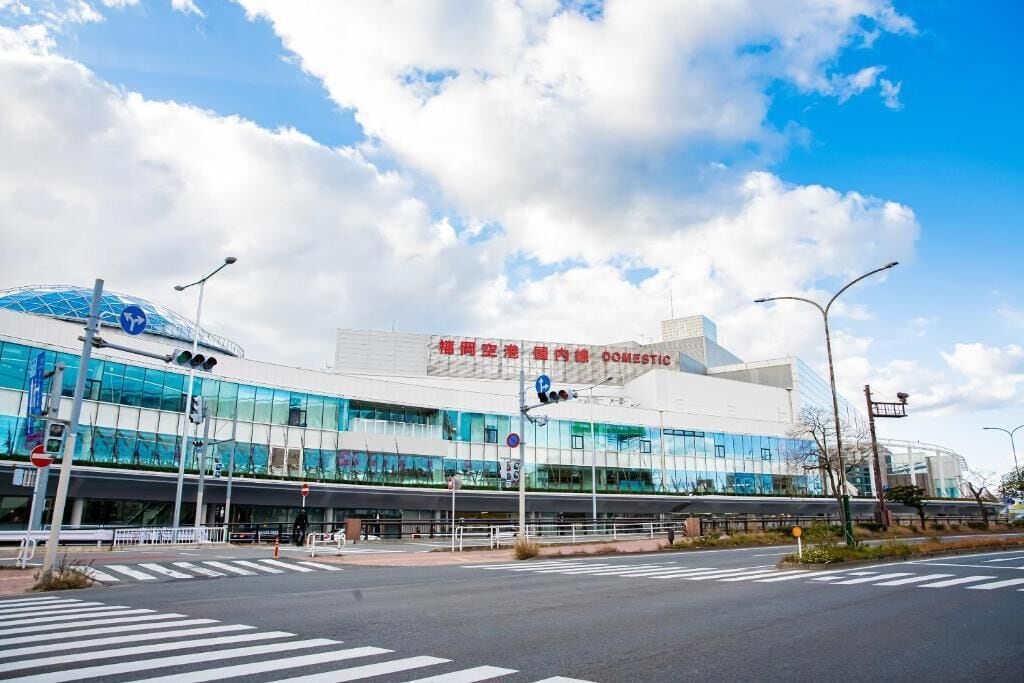 Un edificio moderno con fachada de vidrio, una estructura en forma de cúpula y señalización que indica un aeropuerto nacional.