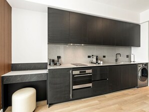 A modern kitchen with dark cabinetry, a countertop, a built-in oven, and a washing machine. - Luxe E11EVEN Downtown Miami Condo - Resort Pool & Amenities (Miami)