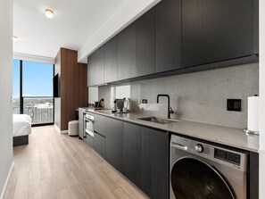 A modern kitchen with a built-in washer and dryer, a large window, and a city view. - Luxe E11EVEN Downtown Miami Condo - Resort Pool & Amenities (Miami)
