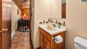 Ein Badezimmer mit einem Holzkonsolenunterschrank, einer Toilette, einem Waschbecken und einem Spiegel.