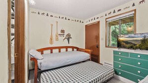 Ein Schlafzimmer mit einem Bett, einer Kommode, einer Wanddekoration und einem Fenster mit Blick.