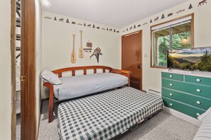 A bedroom with a bed, a dresser, a wall decal, and a window with a view. - Limber Pine Townhome and 2BDR Stay (Whitefish)