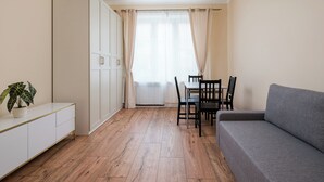 Um espaço compacto com cozinha compacta, uma mesa de jantar com cadeiras, um sofá e um vaso de planta.