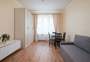 Ein kompakter Wohnraum mit Küchenzeile, einem Esstisch mit Stühlen, einer Couch und einem Topfpflanzen.