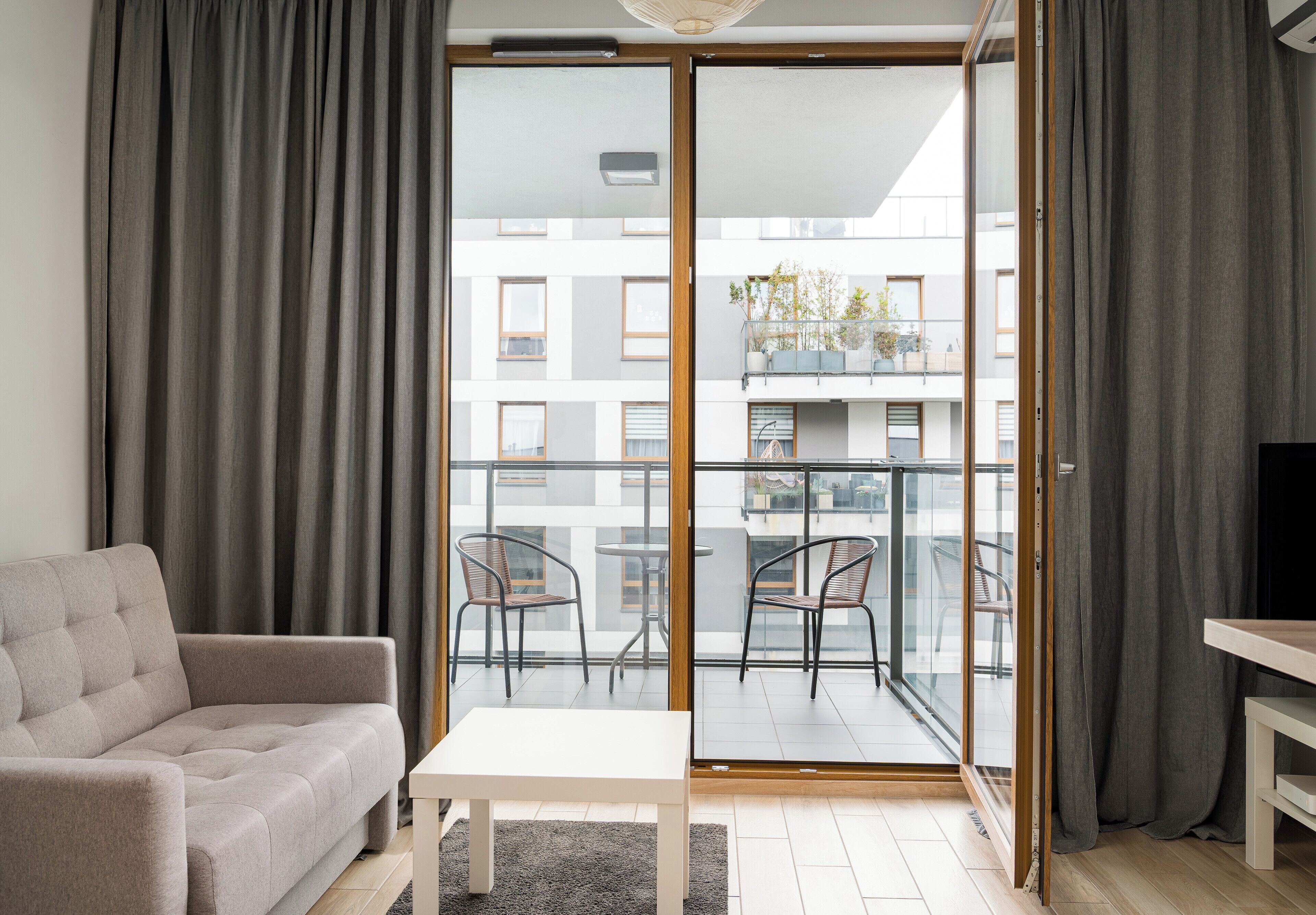 Un salon moderne avec un canapé, une petite table et un balcon équipé de chaises.