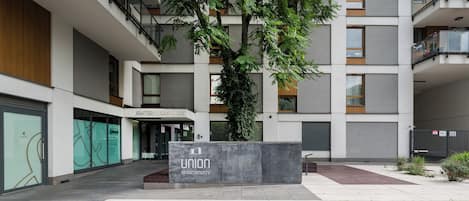 En moderne lejlighedsbygning med et skilt der siger 'Union Apartment' og et træ i midten.