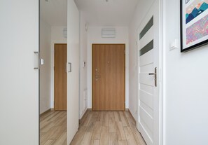 Ein Flur mit Holzboden, weißen Wänden und einer Holztür mit Griff.