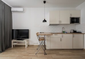 Eine moderne Küche mit Flachbildfernseher, Esstisch und Mikrowelle.
