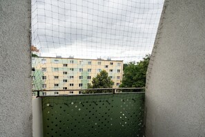Blick durch ein Drahtgitterfenster auf ein mehrstöckiges Gebäude mit grüner Fassade und zahlreichen Fenstern.