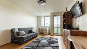 En moderne stue med sofa, fjernsyn, et træskab og et skrivebord.