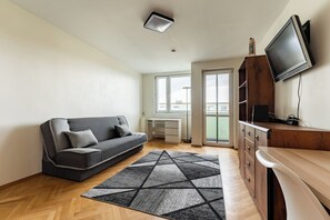 A modern living room with a sofa, a TV, a wooden cabinet, and a desk. - Baltic Seaside Homely Apartment (Gdańsk)