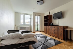 Ein Schlafzimmer mit einem Bett, Nachttischen, einem Kleiderschrank, einem Fernseher und einem Fenster.