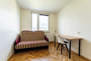 A small, furnished room with a sofa, a table, and a chair. - Baltic Seaside Homely Apartment (Gdańsk)