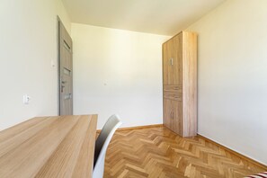 A room with a wooden table, a chair, a wardrobe, and a door. - Baltic Seaside Homely Apartment (Gdańsk)