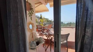 An outdoor patio area with a table and chairs, a hanging plant, and a decorative mirror. - Apartment with a sea views in Levantina, Sitges (Sitges)