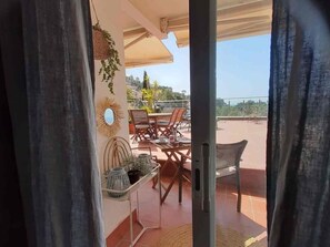 An outdoor patio area with a table and chairs, a hanging plant, and a decorative mirror. - Apartment with a sea views in Levantina, Sitges (Sitges)