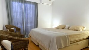 A bedroom with a bed, a chair, and a window with curtains. - Apartment with a sea views in Levantina, Sitges (Sitges)
