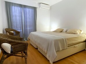 A bedroom with a bed, a chair, and a window with curtains. - Apartment with a sea views in Levantina, Sitges (Sitges)