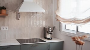 A kitchen with a white range hood, a coffee machine, and a window with a view. - Penthouse, 200m from the beach w/ parking (Cubelles)