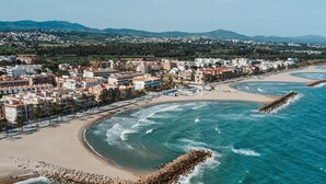 A coastal cityscape with a beach, buildings, and a rocky breakwater. - Penthouse, 200m from the beach w/ parking (Cubelles)