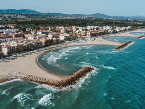 A coastal cityscape with a beach, buildings, and a rocky breakwater. - Penthouse, 200m from the beach w/ parking (Cubelles)