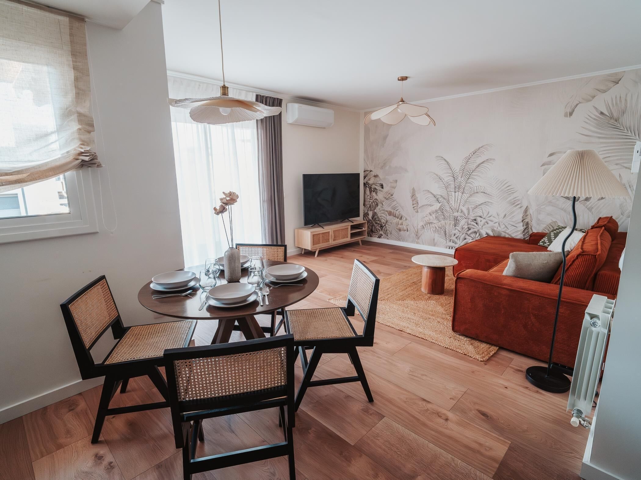 Ein modernes Wohnzimmer mit Essbereich, einer Couch, einem Fernseher und einer Heizung.