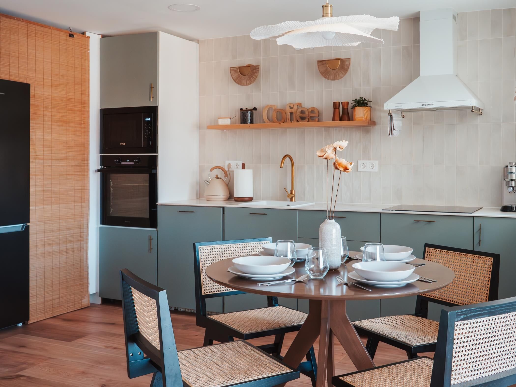 A modern kitchen with a round dining table, chairs, and a hanging light fixture.