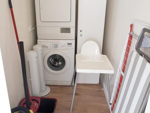 Uma lavanderia compacta com máquina de lavar, secadora e um banquinho pequeno.
