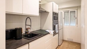 Eine kleine Küche mit Spüle, Kaffeemaschine, Mikrowelle und Kühlschrank.