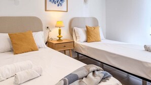 A hotel room with two beds, a bedside table with a lamp, and a wall-mounted artwork. - Pink Las Olas Apartment (Punta Prima)