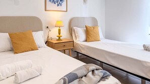 Ein Hotelzimmer mit zwei Betten, einem Nachttisch mit Lampe und einem an der Wand hängenden Kunstwerk.