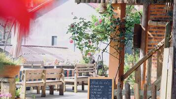 Un espace extérieur aménagé avec des bancs en bois et un tableau noir servant de menu.
