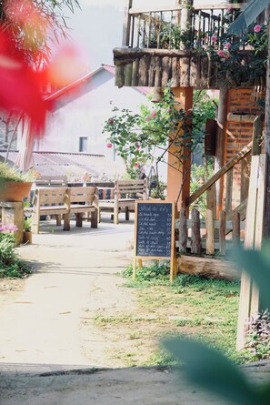 An outdoor seating area with wooden benches and a chalkboard menu.