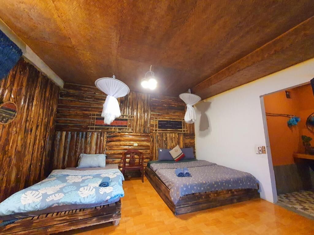 A room with two beds, wooden walls, and a ceiling with exposed beams.