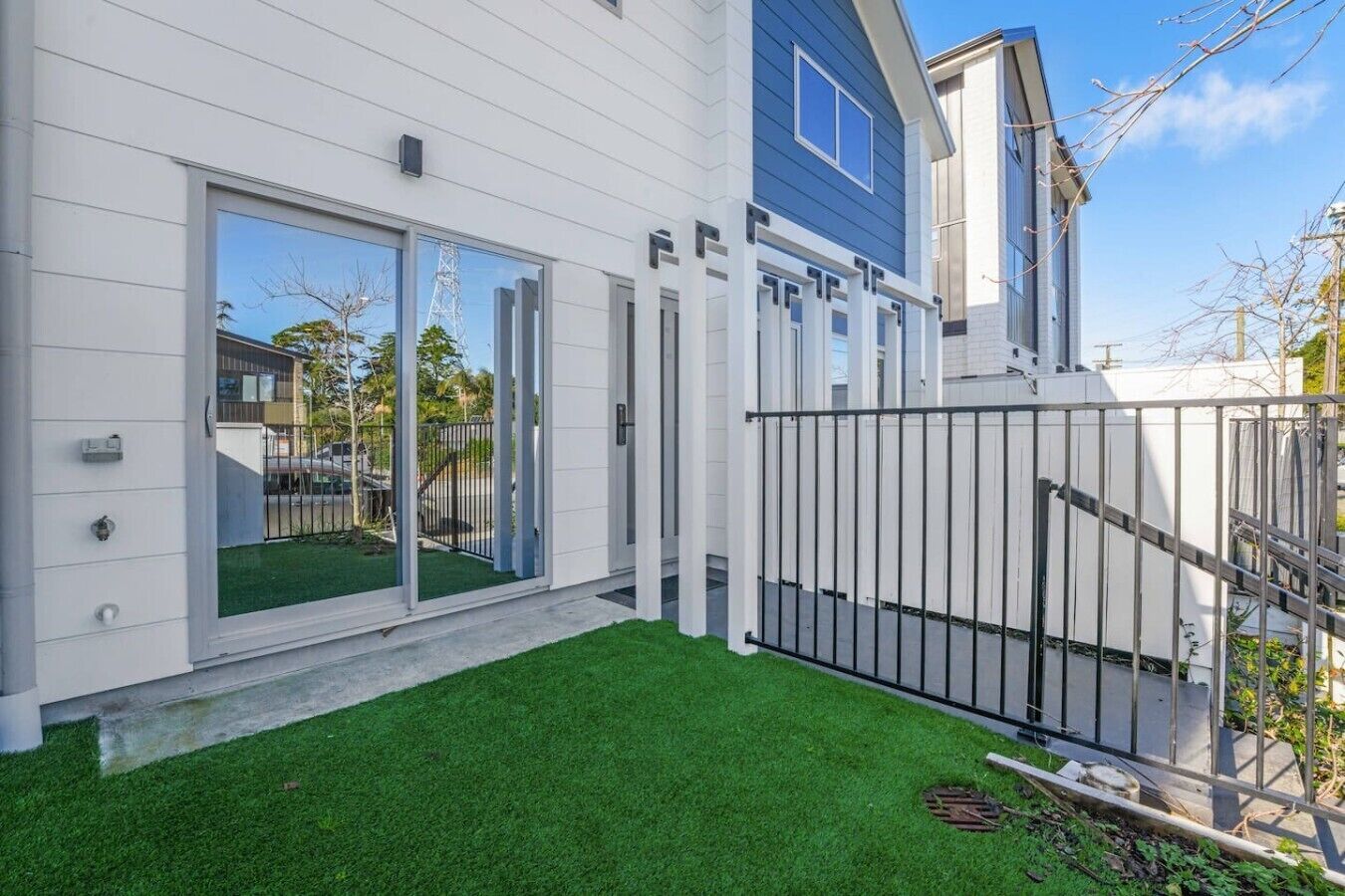 A modern house with a white exterior, a blue accent wall, and a well-maintained lawn.