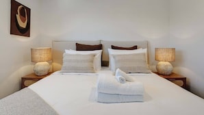 A hotel room with a large bed, two bedside tables, two lamps, and a painting on the wall.