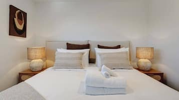A hotel room with a large bed, two bedside tables, two lamps, and a painting on the wall.
