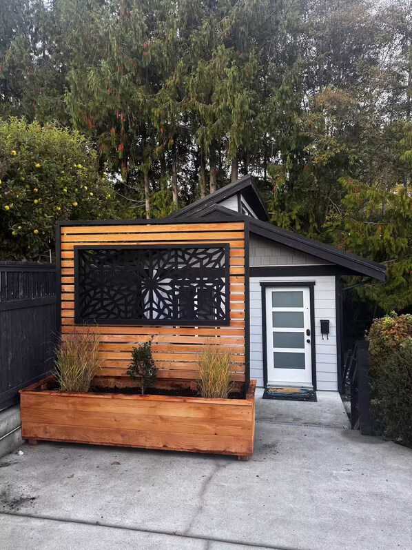 A modern house with a wooden facade, a decorative black lattice panel, and a white door.