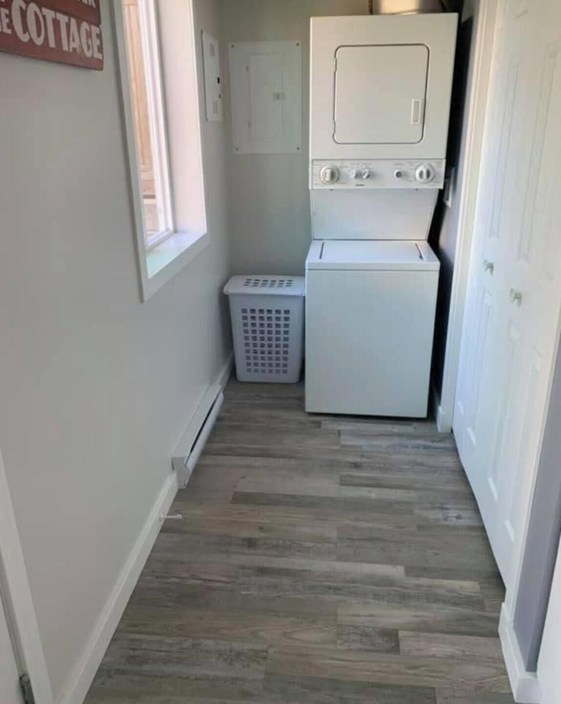 A laundry room with a washer and dryer, a laundry basket, and a sign on the wall.