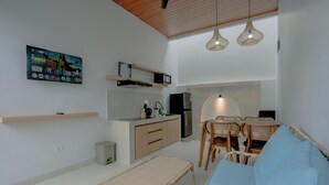 Un espacio habitable compacto con kitchenette, comedor y asientos.