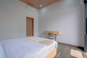 Un dormitorio con cama, un escritorio de madera, una silla y piso de madera.
