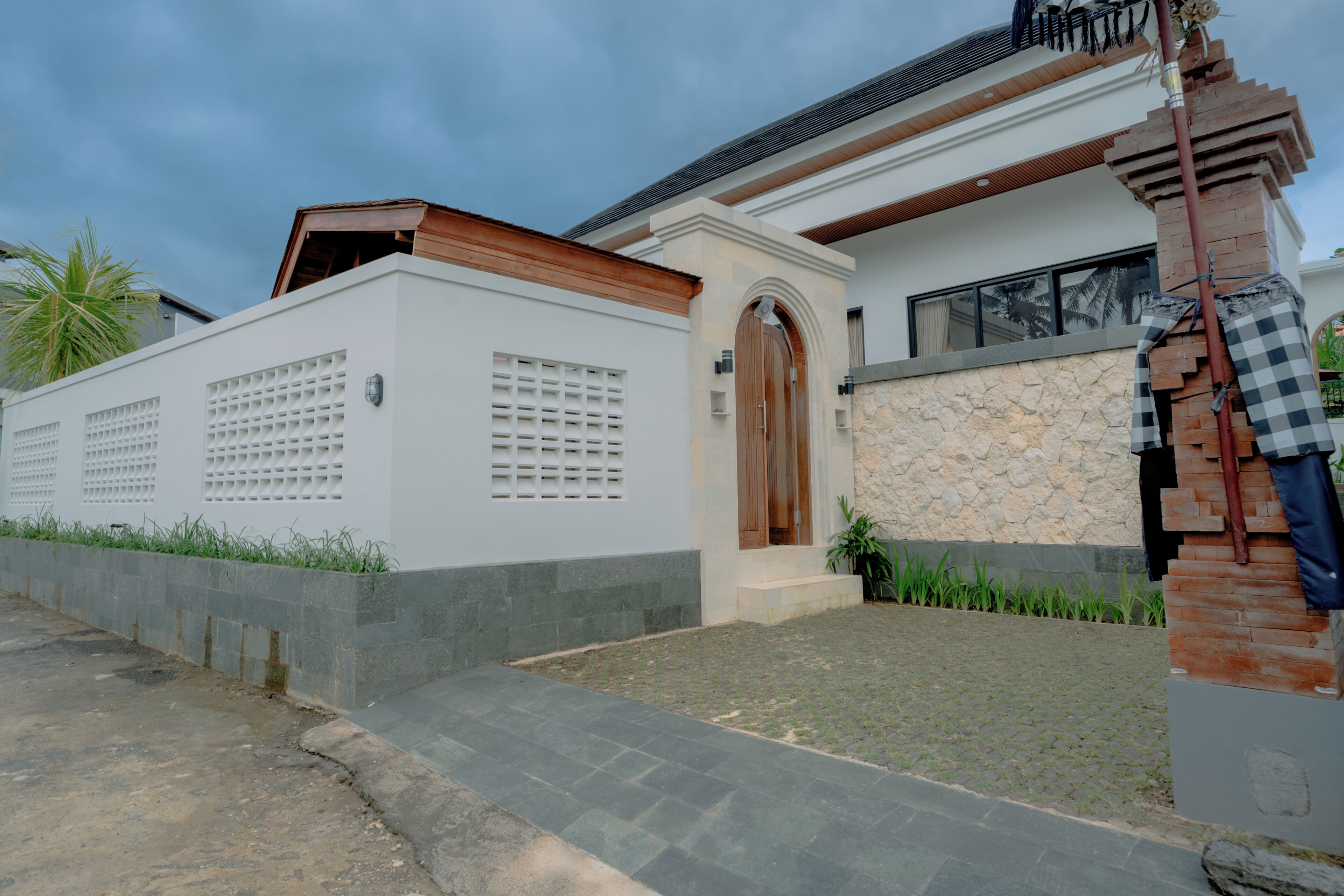 A modern house with a white exterior, a stone accent wall, and a wooden door.