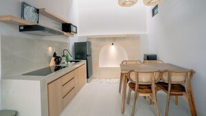 Una cocina moderna con comedor, armarios de madera, microondas integrado y salpicadero de piedra.